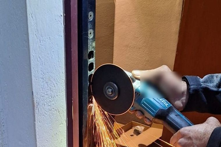 Telaio di una porta blindata con i fori dei catenacci, durante il taglio