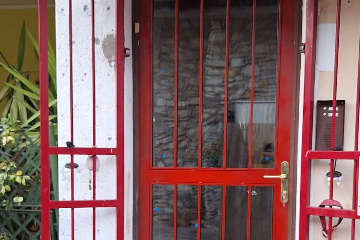Porta d’ingresso in ferro verniciato rosso con inferriata a protezione