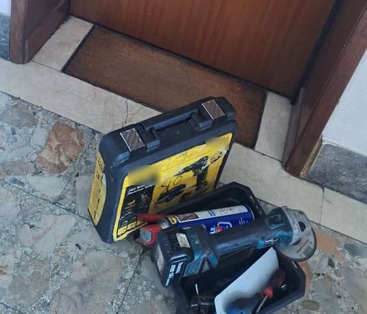 Cassetta degli attrezzi aperta sulla soglia di una porta d’ingresso chiusa, durante un intervento di apertura