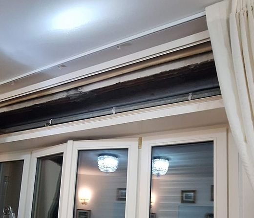 Cassonetto di una tapparella aperto sopra una portafinestra, con la scala appoggiata
